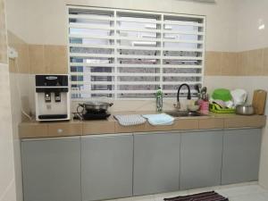 cocina con encimera con fregadero y ventana en Happy homestay sitiawan en Sitiawan