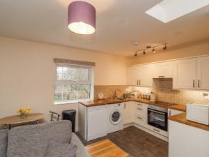 a kitchen with white cabinets and a table and a window at Stable End Cottage in Spilsby