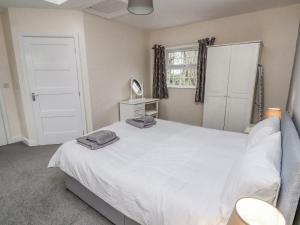 a bedroom with a large white bed and a window at Stable End Cottage in Spilsby