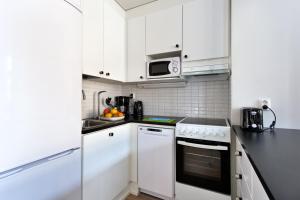 a white kitchen with white cabinets and a microwave at Forenom Serviced Apartments Helsinki Kruununhaka in Helsinki