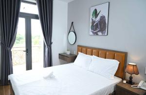 een slaapkamer met een bed met witte lakens en een raam bij HAPPY HOTEL Kien Giang in Ấp Rạch Mẹo