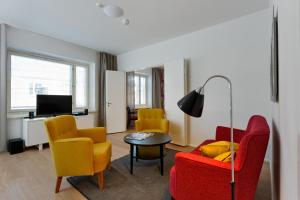 a living room with yellow and red chairs and a table at Forenom Serviced Apartments Helsinki Kruununhaka in Helsinki