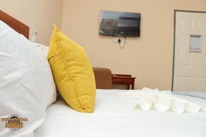 uma cama com uma almofada amarela e uma televisão na parede em The Hill Bed and Breakfast em Francistown