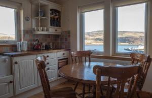 a kitchen with a table and chairs and windows at Bay View Bungalow in Uig