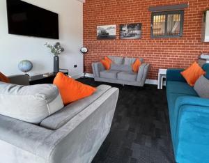 a living room with two couches and a brick wall at Withers Farm Apartments in Mount Bures