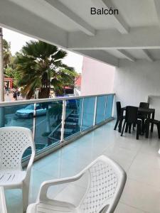 uma varanda com cadeiras e mesas e uma palmeira em Espectaculares Aptos Hansa Coral San Andres Islas em San Andrés