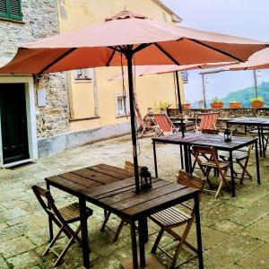 grupa stołów i krzeseł z parasolem w obiekcie Corte Paganini Casa Vacanze w mieście Riccò del Golfo di Spezia