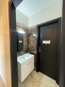 un bagno con porta nera e lavandino bianco di Appartement en résidence privée a Marrakech