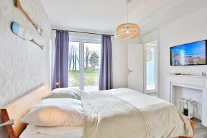 een witte slaapkamer met een bed en een raam bij Haus Meeresbrise Haus Meeresbrise Appartement 1 in Haffkrug