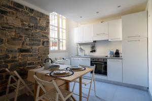 a kitchen with white cabinets and a stone wall at Home Waves Como in Como