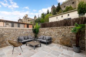 un patio con mobili e una parete in pietra di Au Puits de la Cité - Terrasse Vue Cité - Wifi a Carcassonne