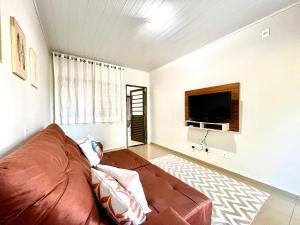 Una sala de estar con un sofá marrón y un televisor de pantalla plana. en Casa Jardim Cataratas na região dos Atrativos, en Foz do Iguaçu
