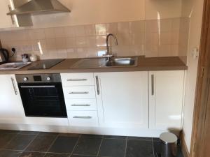 une cuisine avec des armoires blanches et un évier dans l'établissement Nuneaton - Cottage - Sleeps 2 - Parking - Garden, à Nuneaton 20 autres photos