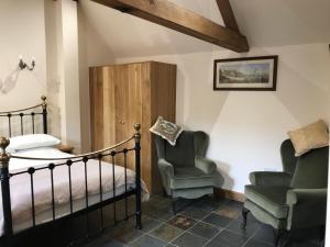 um quarto com uma cama e 2 cadeiras em Lovely 1-Bed Cottage in Nuneaton em Nuneaton