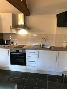 a kitchen with white cabinets and a sink at Lovely 1-Bed Cottage in Nuneaton in Nuneaton