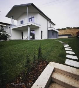 ein großes weißes Haus mit einem Rasenplatz in der Unterkunft Villa Oliveto 24 in Bardolino