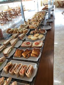 a buffet line with many different types of bread and pastries at Pousada Atlantic Sun in Bertioga