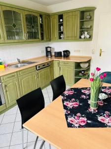 una cucina con armadi verdi e un tavolo con fiori di Ferienwohnung Jahnke a Ostseebad Karlshagen