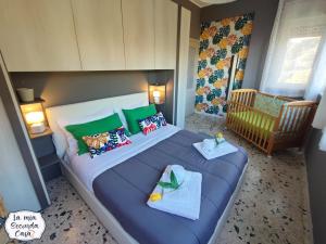 a bedroom with a bed with green pillows and a crib at La mia seconda casa ad Aci Castello in Aci Castello