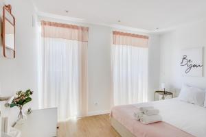 um quarto branco com uma cama com duas toalhas em Cruzeiro Charm Apartments em Lisboa