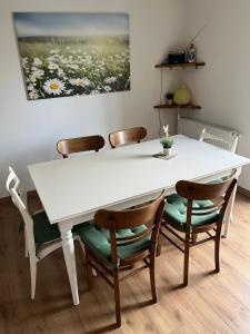 een witte tafel en stoelen met een witte tafel en een schilderij bij Heckenstübchen in Simmerath