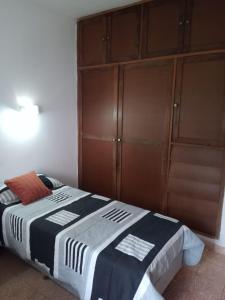 1 dormitorio con 1 cama y armario de madera en Córdoba - La Cumbre -Casa Temporario -Vista Cristo en La Cumbre
