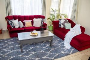 uma sala de estar com dois sofás vermelhos e uma mesa de centro em The White Dove - At Migaa Golf Estate em Kiambu