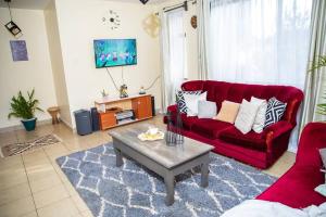 uma sala de estar com um sofá vermelho e uma mesa de centro em The White Dove - At Migaa Golf Estate em Kiambu