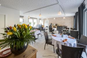 ein Esszimmer mit Tischen, Stühlen und einer Vase aus Blumen in der Unterkunft Il Nido in Ernolsheim-Bruche