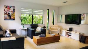 ein Wohnzimmer mit einem Sofa und einem TV in der Unterkunft Design District by Midtown, Wynwood, Brickell, 10 min to the Beach, FREE PARKING in Miami