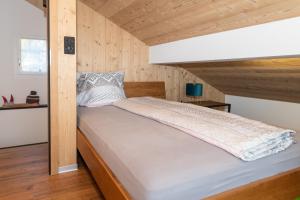 Cama en habitación con paredes de madera en Ferienwohnung, en Staldenried