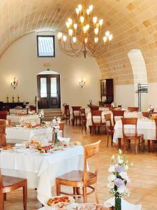 a dining room with white tables and chairs and a chandelier at Masseria Torre Spagnola in Matera