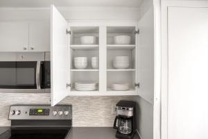 a kitchen with white cabinets and white dishes on shelves at Back Bay 1BR w Gym nr Copley Sq BOS-739 in Boston