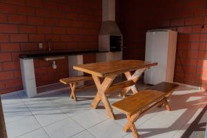 a table and benches in a kitchen with a refrigerator at Martim de Sá - Caragua in Caraguatatuba