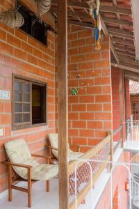 a porch with two chairs and a brick wall at Martim de Sá - Caragua in Caraguatatuba