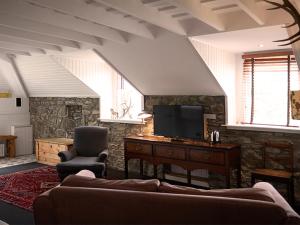 a living room with a couch and a tv at Monachyle Mhor Hotel in Lochearnhead