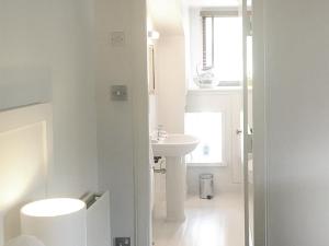 a white bathroom with a sink and a toilet at Monachyle Mhor Hotel in Lochearnhead