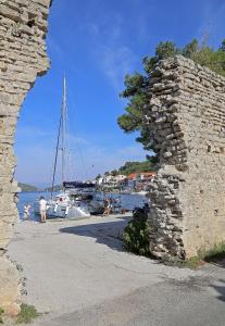 a stone wall next to a harbor with a boat at Apartments Patricija in Polače