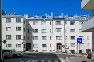 a large white building with a car parked in front of it at Forenom Serviced Apartments Helsinki Kruununhaka in Helsinki