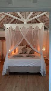 a bedroom with a white bed with a canopy at Ti Cocon Des Iles, Bungalow de Charme Spa Privatif in Quartier du Fond Fleuri