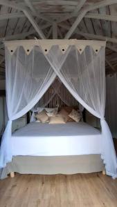 a white bed with a canopy in a room at Ti Cocon Des Iles, Bungalow de Charme Spa Privatif in Quartier du Fond Fleuri