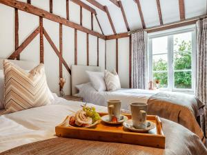 dwa łóżka w pokoju z tacą z jedzeniem na nich w obiekcie The Cottage w mieście Broomfield