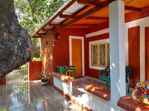 a porch of a red house with a green chair at Alojamiento El Bosque in Cambyretá