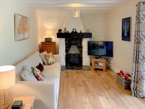 a living room with a white couch and a fireplace at Hollywell Barn in Menheniot