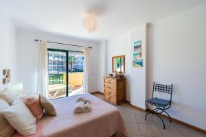 um quarto com uma cama, uma cadeira e uma janela em Beach House Santa Eulália, Albufeira em Albufeira