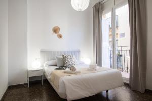 a white bedroom with a bed and a window at Flatsforyou Carmen in Valencia