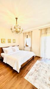 a white bedroom with a large bed and a chandelier at Zrinka House in Grabovac