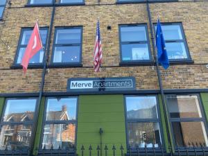 three flags on the side of a brick building at Merve Apartments by Like Your Home LTD in Maidstone