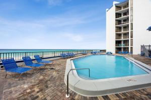 a swimming pool on the beach with chairs and a building at AquaVista Beach Resort by Panhandle Getaways in Panama City Beach