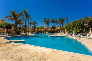 a swimming pool at a resort with palm trees at S'avarqueta in Son Xoriguer